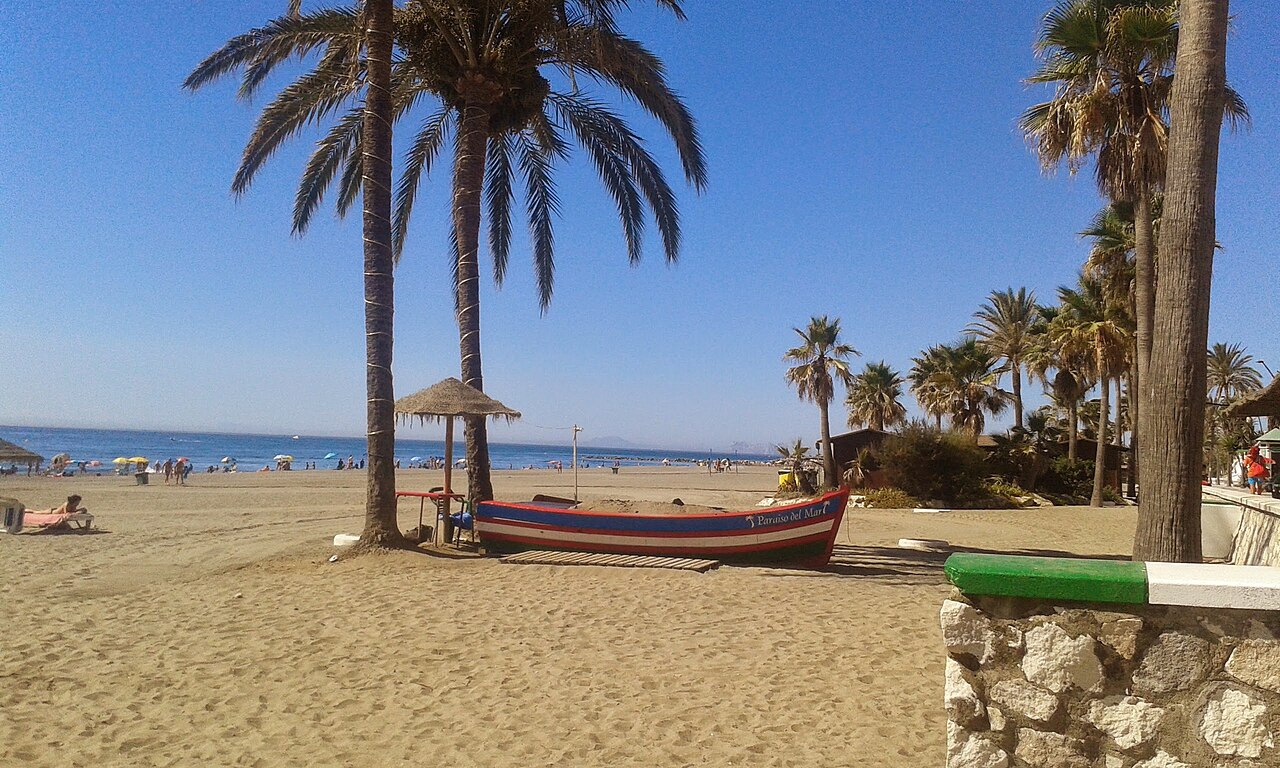 Playa de la Rada in Estepona met palmen en een vissersboot